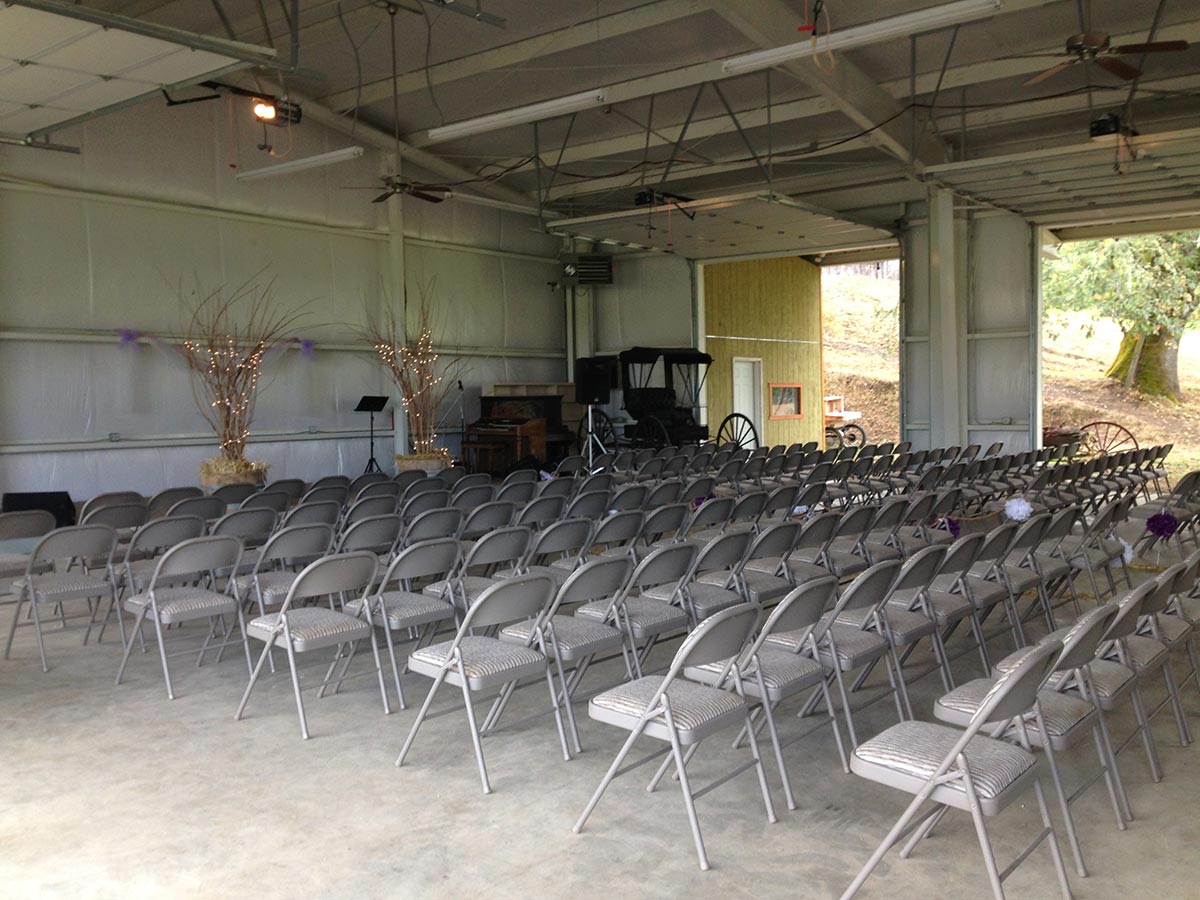 Metal padded chairs are lined up facing a stage with a large barn.